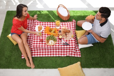 Photo of Happy couple imitating picnic at home, above view