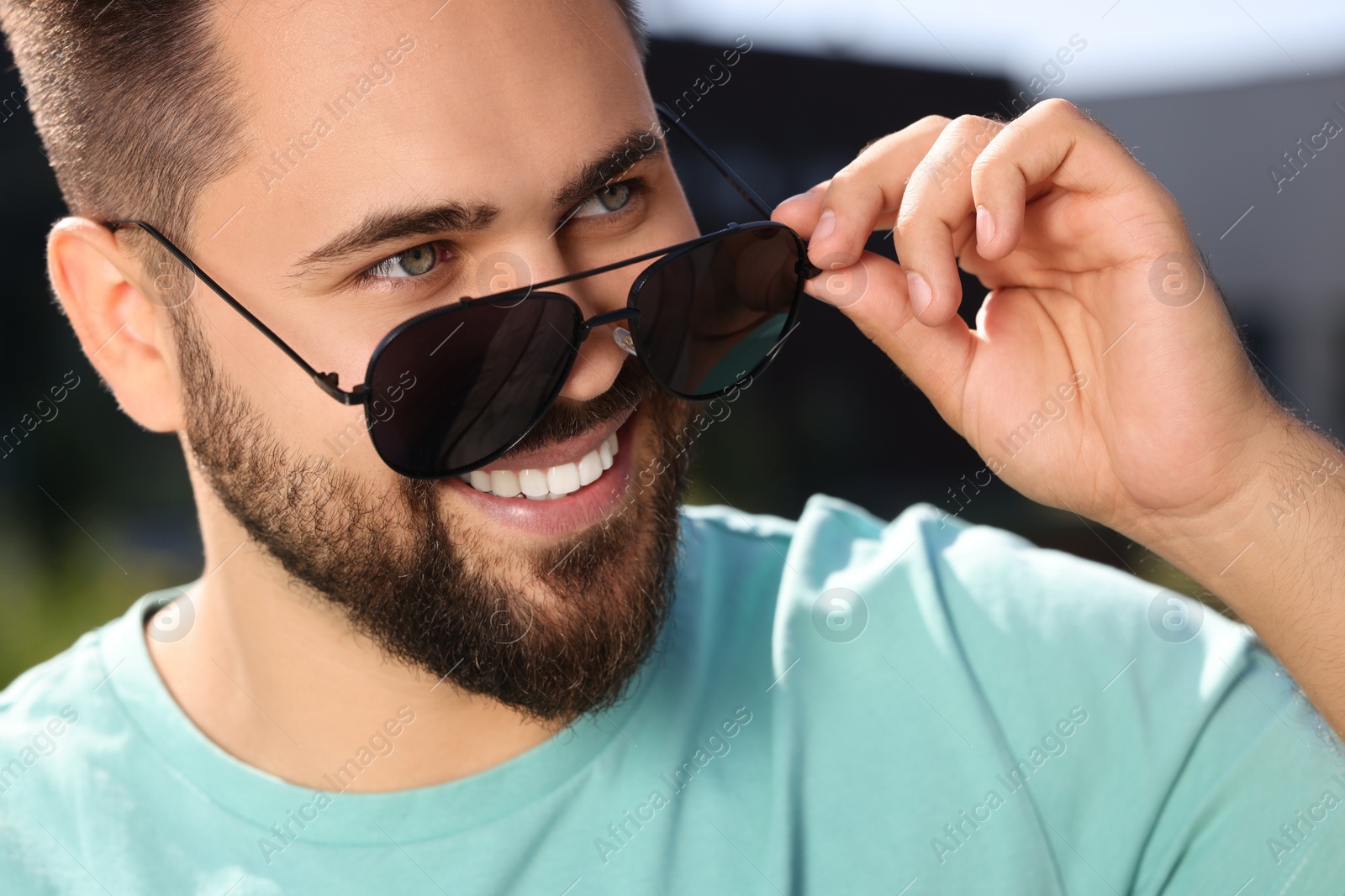 Photo of Handsome smiling man in sunglasses outdoors, closeup