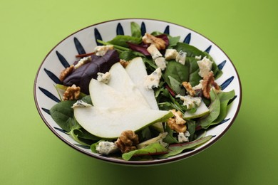 Delicious pear salad in bowl on green background, closeup