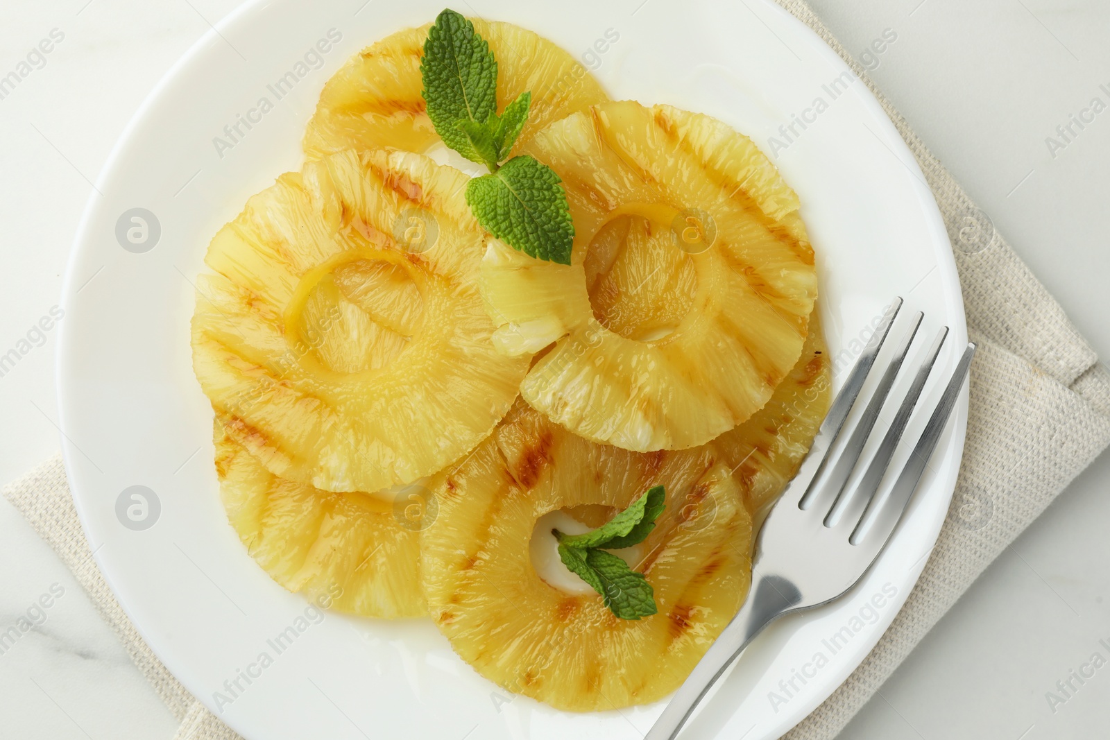 Photo of Tasty grilled pineapple slices and mint on white table, top view
