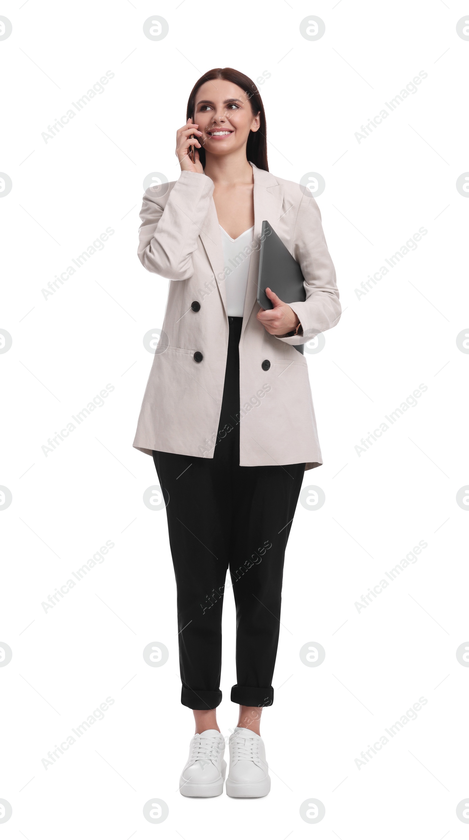 Photo of Beautiful businesswoman in suit with laptop talking on smartphone against white background