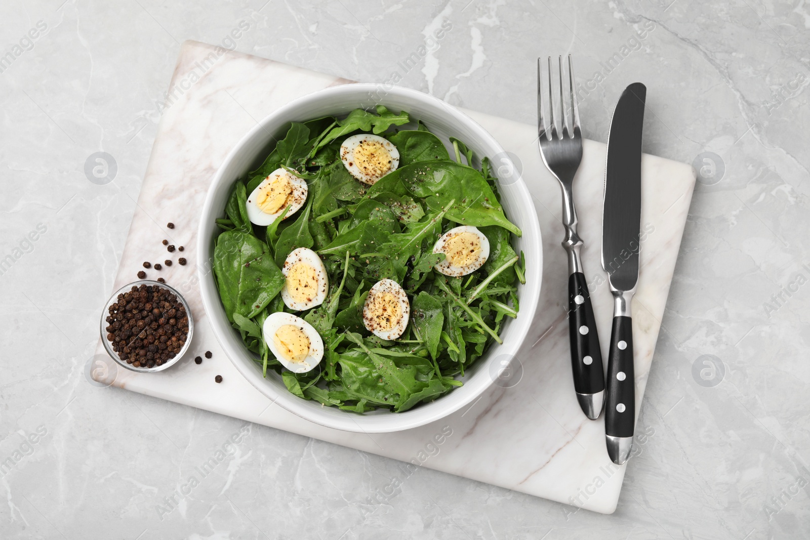 Photo of Delicious salad with boiled eggs and herbs served on light grey marble table, top view