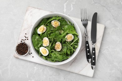 Delicious salad with boiled eggs and herbs served on light grey marble table, top view