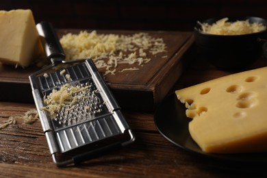 Different types of cheese and grater on wooden table, closeup