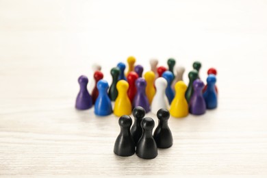 Photo of Colorful game pieces on white wooden table. Racism concept