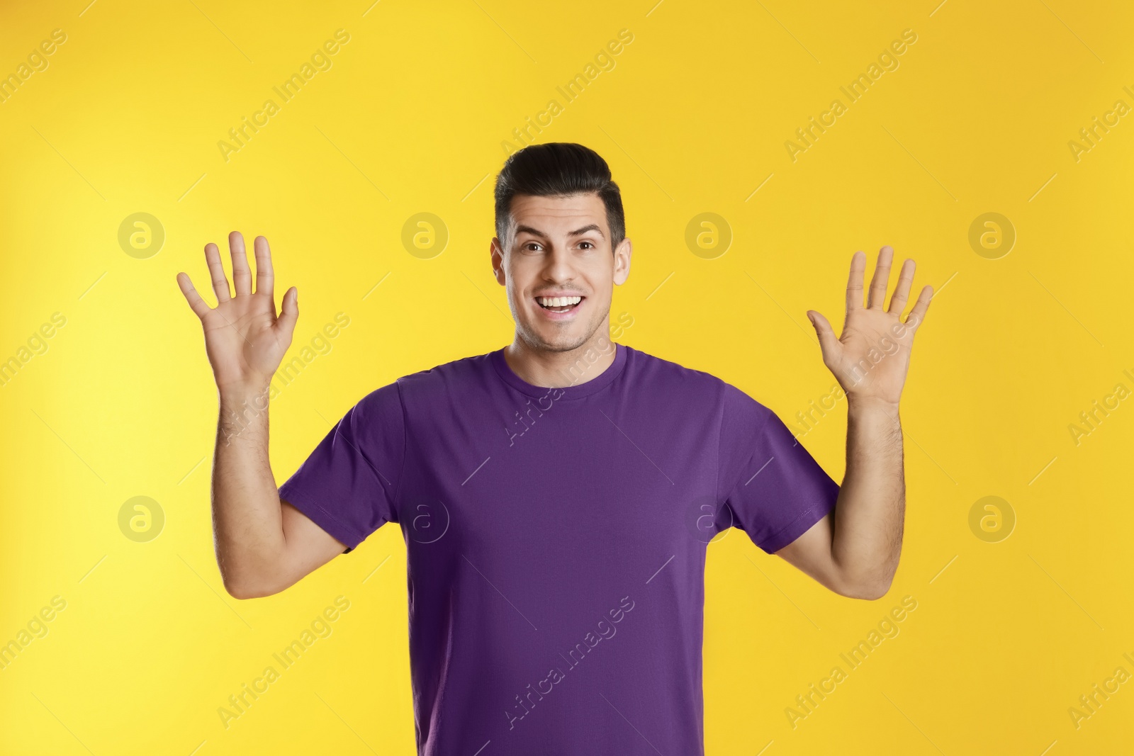 Photo of Cheerful man waving to say hello on yellow  background