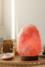 Himalayan salt lamp, candles and crystals on golden table indoors, space for text