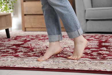 Photo of Woman standing on carpet with pattern at home, closeup