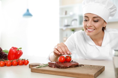 Photo of Professional female chef cooking meat on table in kitchen