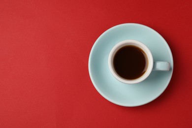 Tasty coffee in cup on red background, top view. Space for text