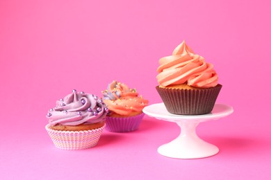 Photo of Delicious cupcakes with bright cream and sprinkles on pink background. Space for text