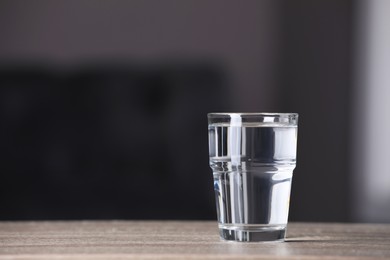 Photo of Glass of pure water on wooden table indoors, space for text
