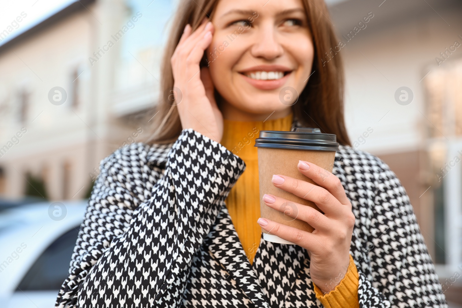 Photo of Young woman with cup of coffee on city street in morning, focus on hand