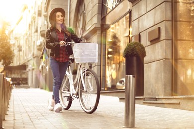 Image of Beautiful happy woman with bicycle in city on sunny day