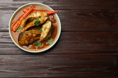 Photo of Tasty fish curry on wooden table, top view. Space for text. Indian cuisine