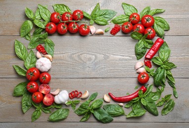 Photo of Frame made of fresh basil leaves and vegetables on wooden table, flat lay. Space for text