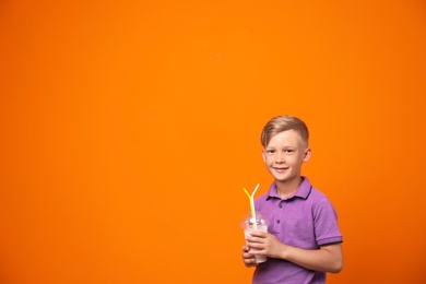 Photo of Little boy with cup of milk shake on color background
