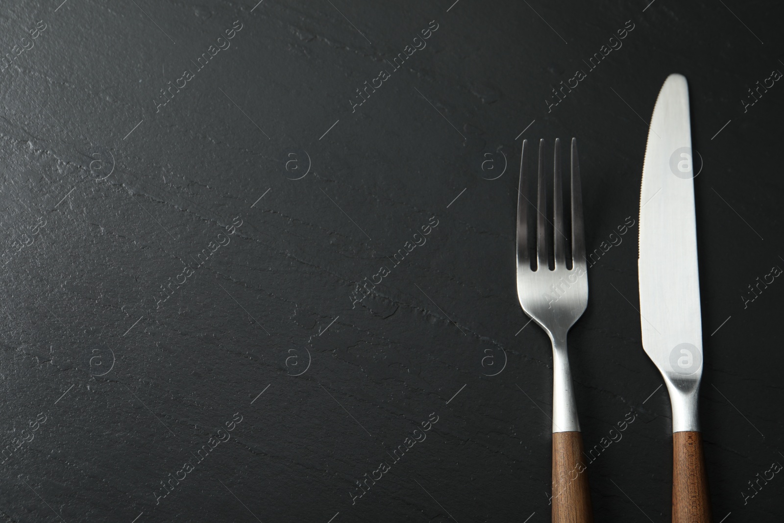 Photo of Stylish cutlery on black table, top view. Space for text