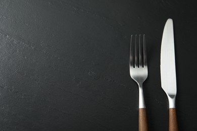 Photo of Stylish cutlery on black table, top view. Space for text