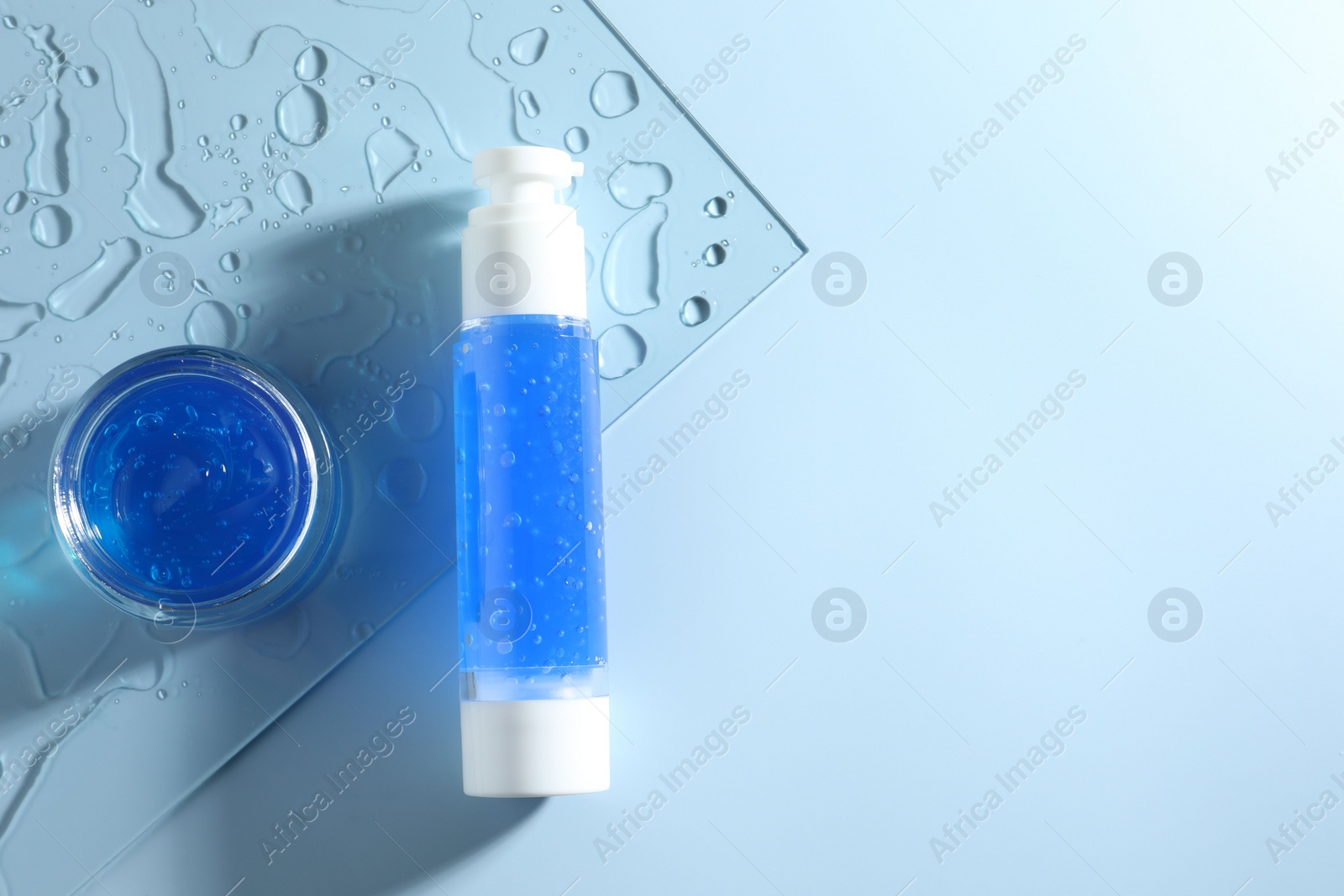 Photo of Bottle and jar of cosmetic products on light blue background, top view. Space for text
