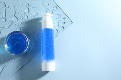 Photo of Bottle and jar of cosmetic products on light blue background, top view. Space for text