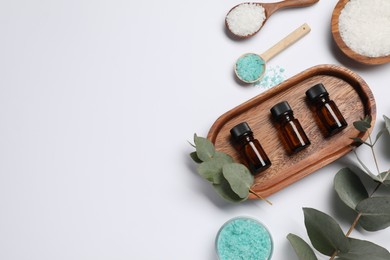 Photo of Aromatherapy products. Bottles of essential oil, sea salt and eucalyptus leaves on white background, flat lay. Space for text