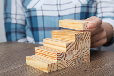 Woman building steps with wooden blocks at table, closeup. Career ladder