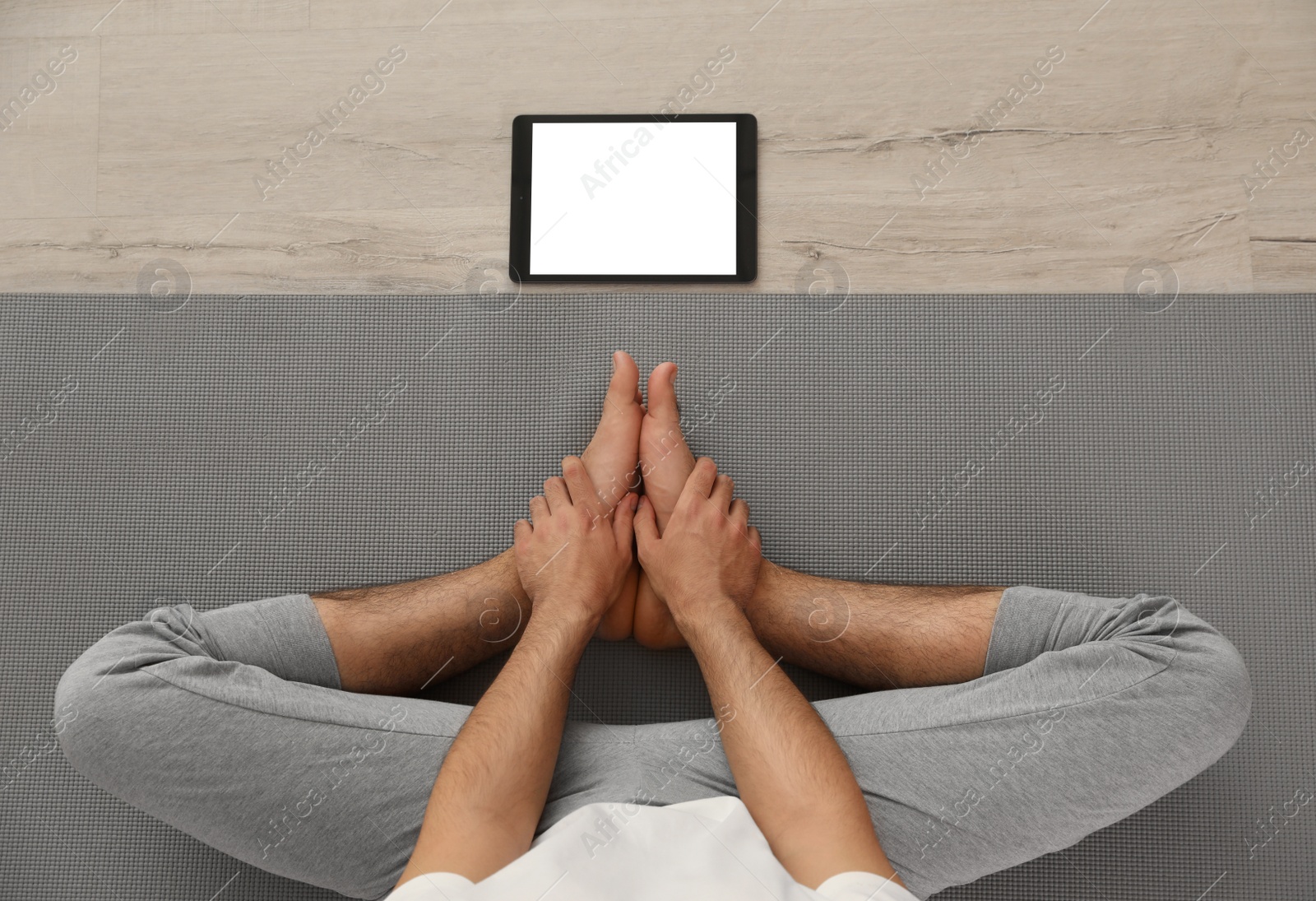 Photo of Man practicing yoga while watching online class at home during coronavirus pandemic, top view. Social distancing