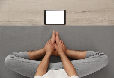 Man practicing yoga while watching online class at home during coronavirus pandemic, top view. Social distancing