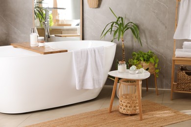 Photo of Modern white tub and beautiful green houseplants in bathroom. Interior design