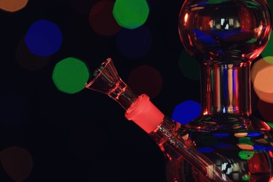 Closeup view of glass bong against blurred lights. Smoking device