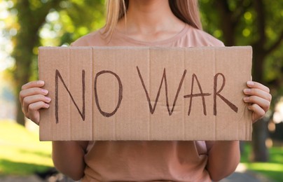 Photo of Woman holding poster with words No War in park, closeup
