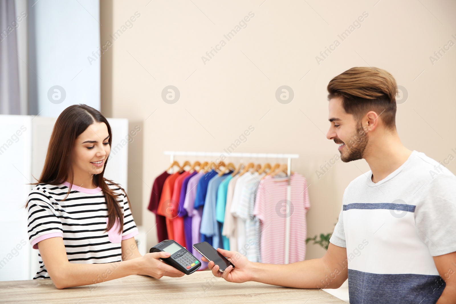 Photo of Man using terminal for contactless payment with smartphone in shop