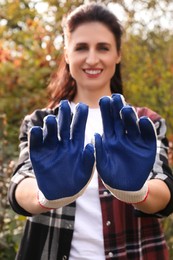 Woman showing protective gloves in garden, focus on hands