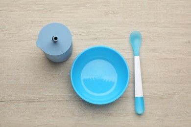 Set of plastic dishware on wooden background, flat lay. Serving baby food