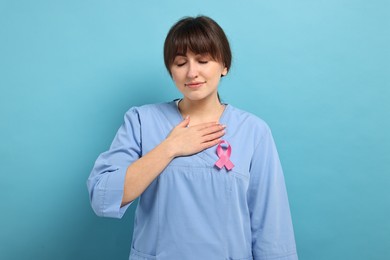 Photo of Mammologist with pink ribbon on light blue background. Breast cancer awareness