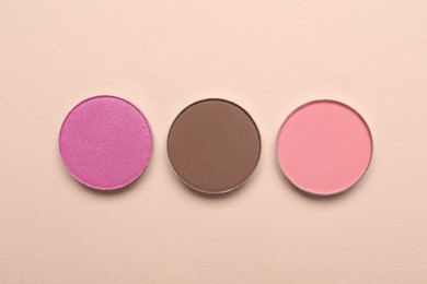 Photo of Beautiful eye shadow refill pans on beige background, flat lay