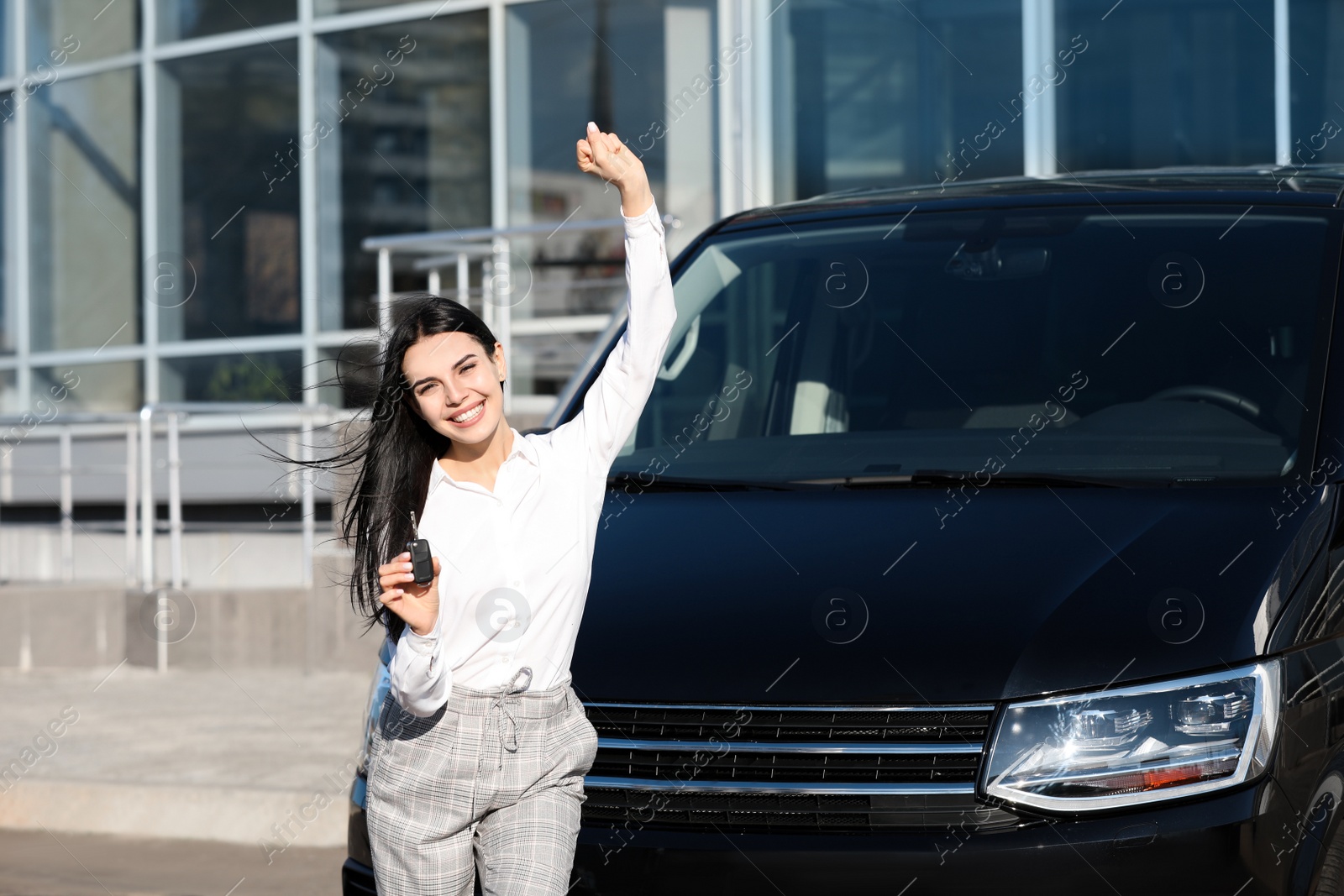 Photo of Young woman with key near car on city street. Buying new auto