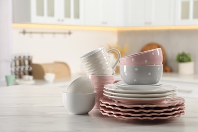 Many different clean dishware and cups on white marble table in kitchen. Space for text