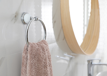 Holder with clean towel on light wall in bathroom