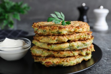 Delicious zucchini fritters served on grey table, closeup