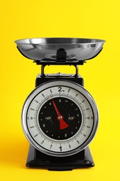 Photo of Retro mechanical kitchen scale on yellow background