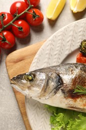 Delicious baked fish and vegetables on light grey table, top view