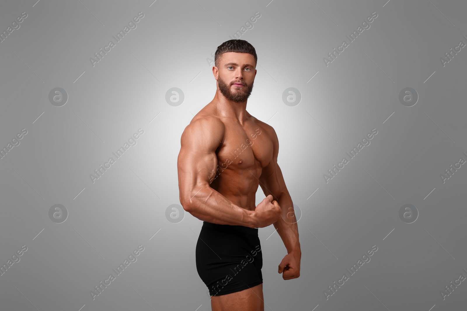 Photo of Young bodybuilder with muscular body on light grey background