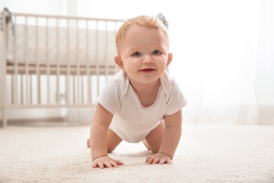 Photo of Cute little baby crawling on carpet indoors