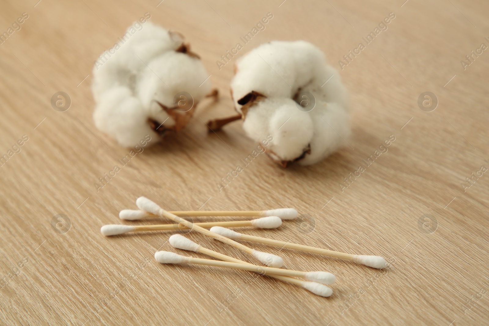 Photo of Cotton swabs and flowers on wooden table, closeup