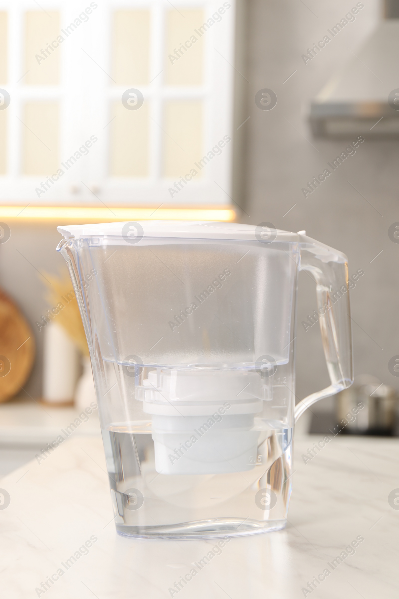 Photo of Water filter jug on white marble table in kitchen