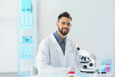 Young scientist with microscope in laboratory. Chemical analysis