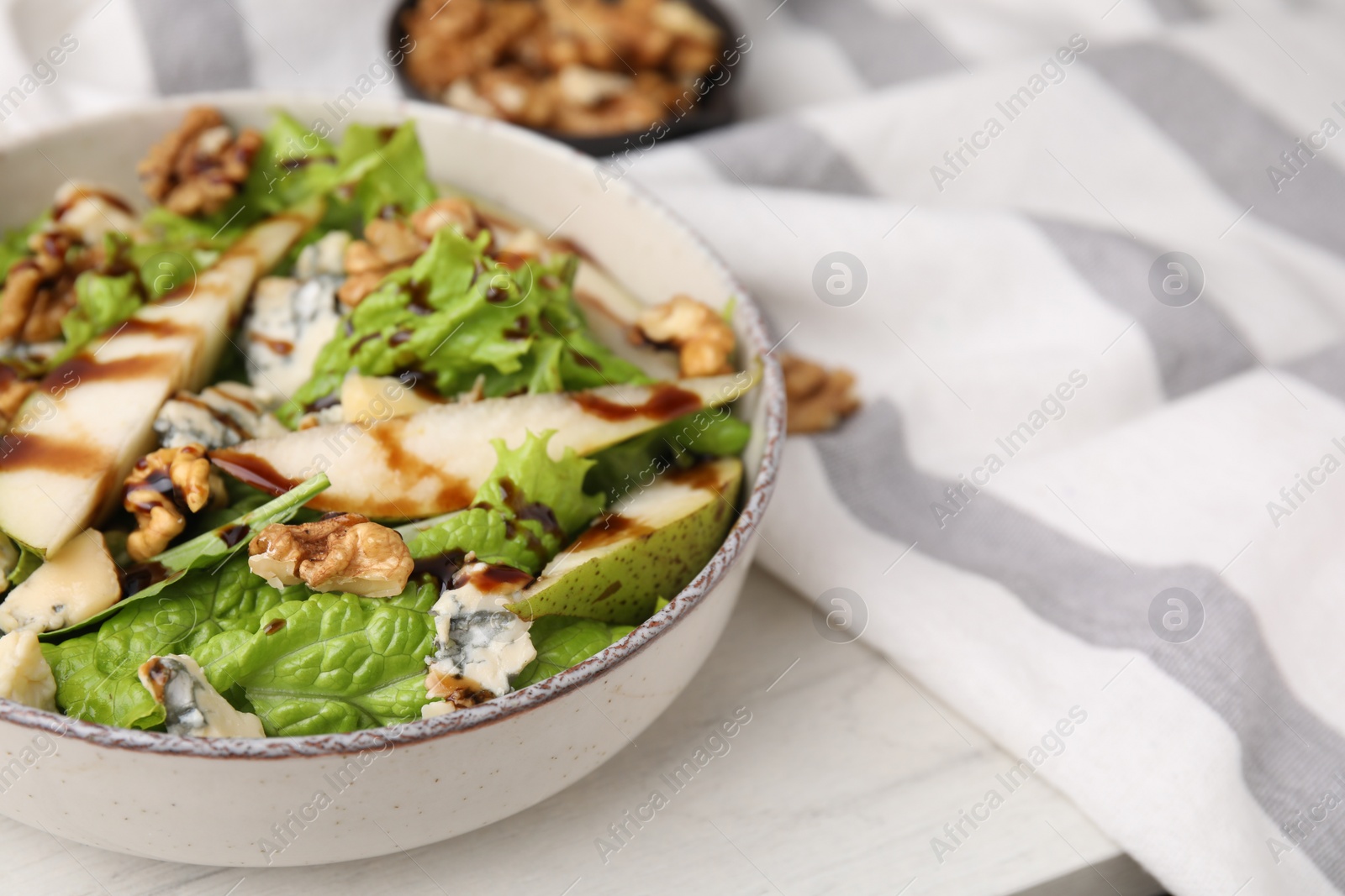 Photo of Delicious pear salad with sauce in bowl on white table, closeup. Space for text