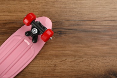 Photo of Pink skateboard on wooden background, top view. Space for text